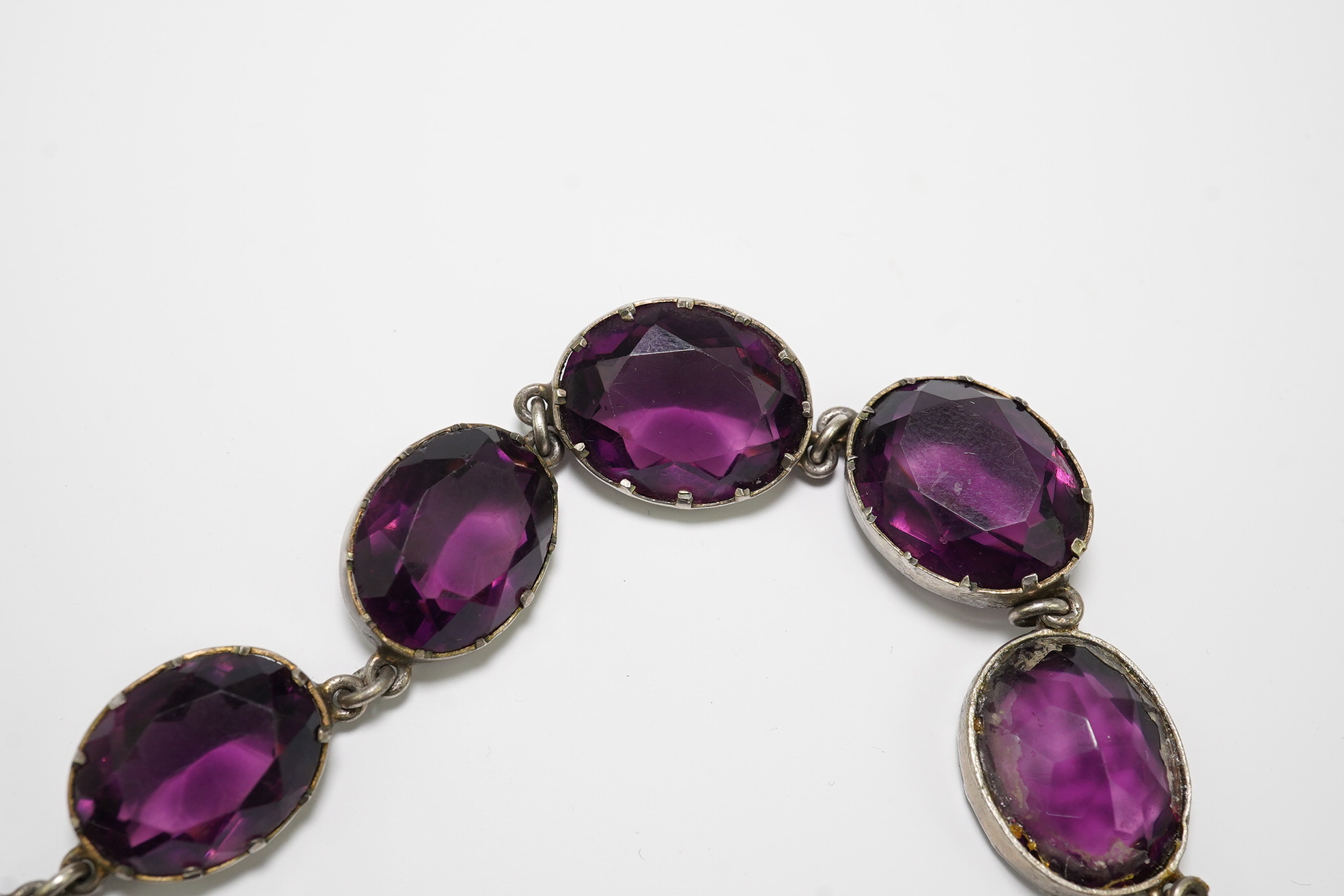 A Victorian silver and graduated oval cut amethyst paste set riviere necklace